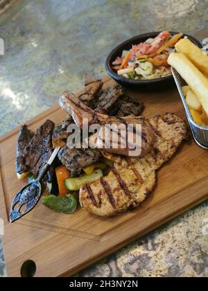 Gemischte Fleischzusammensetzung auf einem Holzbrett. Grillflecken und Gemüse sind köstlich. Stockfoto