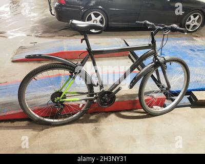 Ein schwarzes Fahrrad in einem Autoreparaturgeschäft. Stockfoto