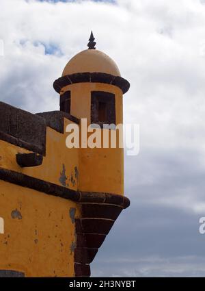 Eine Kuppel an der Ecke der historischen gelben Festung in funchal madeira vor einem strahlend blauen Himmel mit weißen Wolken Stockfoto