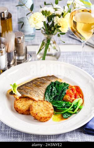 Hechtbarsch-Filet mit Gemüseschnitzel und Gemüse im Restaurant-Setting. Stockfoto