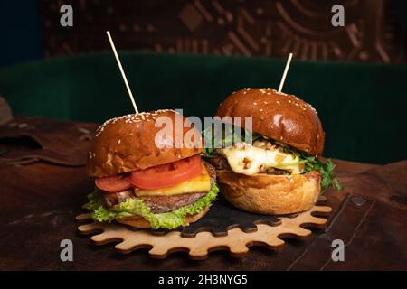 Auf einem dekorativen Holzteil eines einfachen Mechanismus werden eine Doppelte Portion frischer Rinderburger und eine mit frittierten Walnüssen serviert. Stockfoto