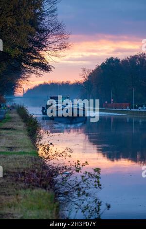 Frachtschiff auf einem Fluss während eines nebligen Sonnenaufgangs Stockfoto