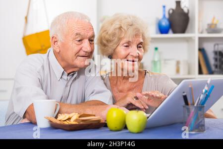 Fröhliche ältere Ehepartner mit Laptop zu Hause Stockfoto