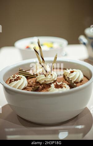 Schokoladenmousse in einem weißen Becher, verziert mit Schokolade und Schlagsahne Stockfoto