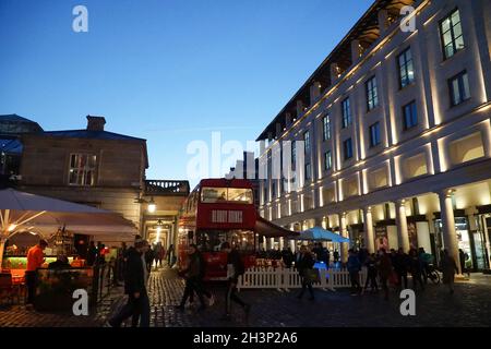 London, Großbritannien, 29. Oktober 2021: Während die Abenddämmerung in Covent Garden und den umliegenden gepflasterten Straßen einbricht, genießen Touristen und Einkäufer einen trockenen Zauber zwischen Regenschauern. Diners und Trinker in Bars, Pubs oder Restaurants haben oft die Wahl, drinnen oder draußen zu sitzen. Werbekampagnen, die Menschen zu einem Besuch in London ermutigen, scheinen viele halbzeitige Familienbesuche angelockt zu haben, und London hat derzeit eine geringere Rate an kovidierten Infektionen als einige andere Gebiete des Landes. Im zentralen Marktbereich sind bereits Weihnachtsdekorationen zu sehen. Anna Watson/Alamy Live News Stockfoto