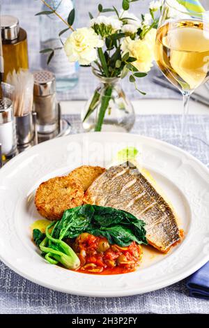 Hechtbarsch-Filet mit Gemüseschnitzel und Gemüse im Restaurant-Setting. Stockfoto