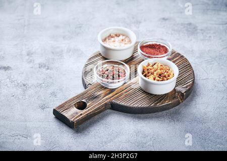 Mischung aus roten und schwarzen Pfefferkörnern, grobem Himalaya-rosa Salz, getrockneten Tomaten und getrockneten Zwiebeln Stockfoto