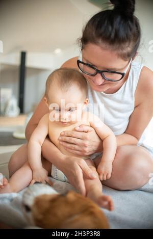 Mutter hält Baby wathing Beagle Hund schlafen. Stockfoto