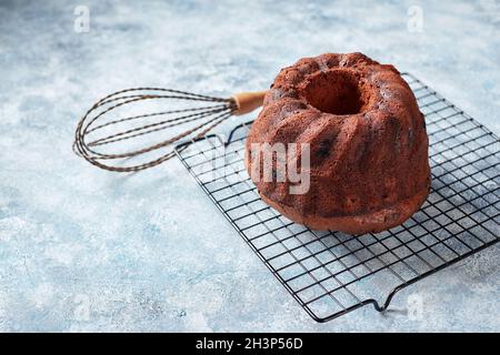 Schokoladenkuchen auf einem Metalldrahtgestell, Puderzucker und Preiselbeeren in Schüsseln Stockfoto