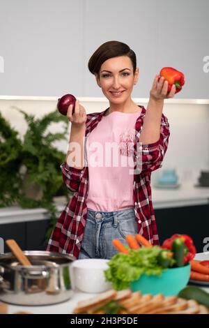 Äpfel in den Händen halten Hausfrau trägt kariertes Hemd mit kurzer Frisur, während sie Apfelkuchen in der Küche kocht Stockfoto