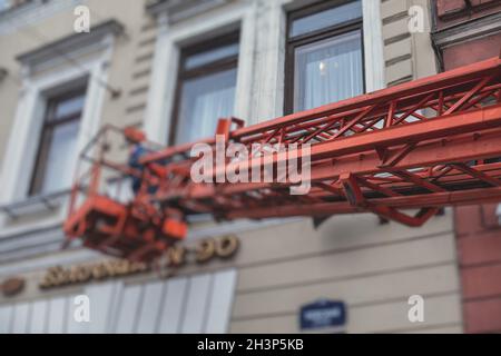 Luftarbeitsbühne Fahrzeug während der Fassade Dekoration, orange Teleskopaufzug auf der Baustelle, Vermietung AWP arbeiten in den Straßen der Stadt, Motor Stockfoto