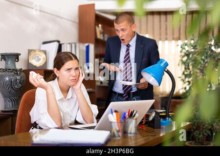 Ein junger Geschäftsmann schimpft sein Mädchen im Büro Stockfoto