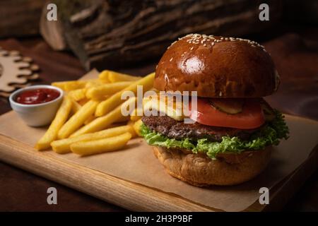 Rindfleisch-Burger serviert mit pommes Frites dekorativen Holztisch und Tomatensauce in der Sauce Schüssel. Restaurantkonzept. Fast Food CO Stockfoto