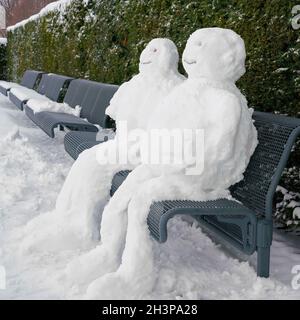 Schneemann und Schneefrau auf einer Parkbank in Magdeburg in Winter Stockfoto