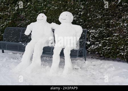 Schneemann und Schneefrau auf einer Parkbank in Magdeburg in Deutschland im Winter Stockfoto