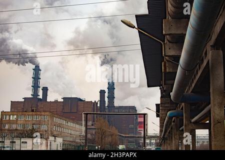 Schädlicher Rauch aus den Rohren des Metallwerks. Betonstützen und Drähte. Stockfoto