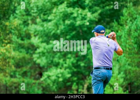 Blick von hinten, ein Mann spielt Golf auf einem Waldgrund. Hochwertige Fotos Stockfoto