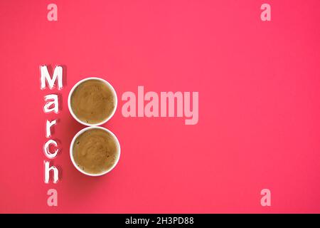 Zwei Pappbecher Morgenkaffee in Form der Nummer 8. Auf einem roten Hintergrund. Die Inschrift ist März 8. Layout. Copy Spa Stockfoto
