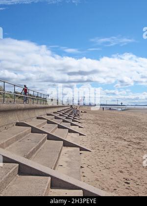 Menschen am Strand von blundell Sands in crosby in der Nähe von southport merseyside mit Geländern am Meer und Liverpools Docks Stockfoto
