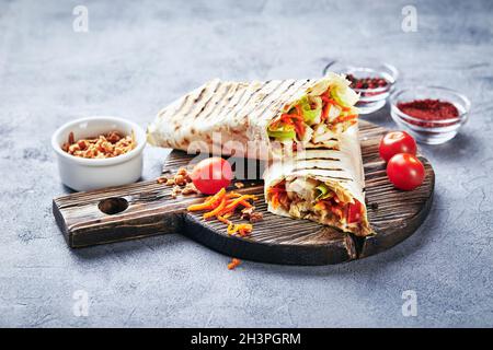 Traditionelle Shawarma aus dem Osten mit Huhn und Gemüse, Döner Kebab mit Saucen auf Holzschneidebrett. Stockfoto