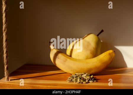 Pistazien, Banane und Birne. Gesunde Ernährung. Frucht im Sonnenlicht. Stillleben der gelben Früchte. Stockfoto