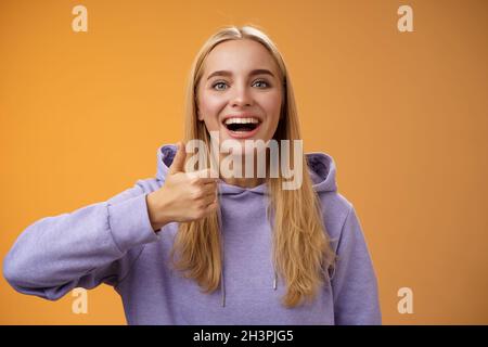 Unterstützend glücklich froh junge blonde attraktive Frau im Hoodie adore perfekt gute Idee zeigen Daumen nach oben Zustimmung wie Geste Smilie Stockfoto