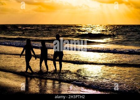 Sonnenuntergang am Mittelmeer. Die Sonnenstrahlen reflektierten sich im Wasser. Silhouetten von Menschen, die zu Fuß gehen Stockfoto