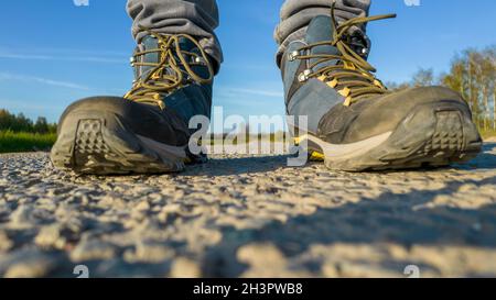 Füße von Reisenden, die Trekkingschuhe tragen, auf der Straße Nahaufnahme Stockfoto