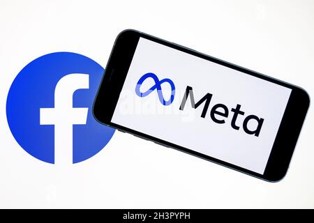 META-Firmenlogo auf dem Smartphone in der Hand mit Facebook-Logo auf dem Hintergrundbildschirm gesehen. Neues Facebook-Firmenlogo für METAVERSE. Stockfoto
