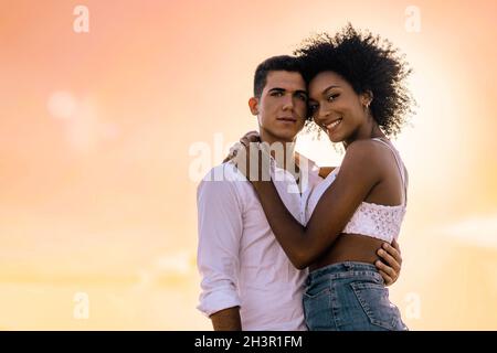 Multirassisches Paar schöner junger Liebhaber, die sich bei Sonnenuntergang umarmen - Konzept der multikulturellen Liebe im Urlaub Stockfoto