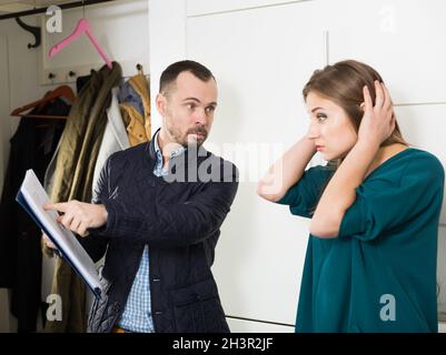 Frustrierte Frau im Gespräch mit dem Schuldeneinnehmer Stockfoto