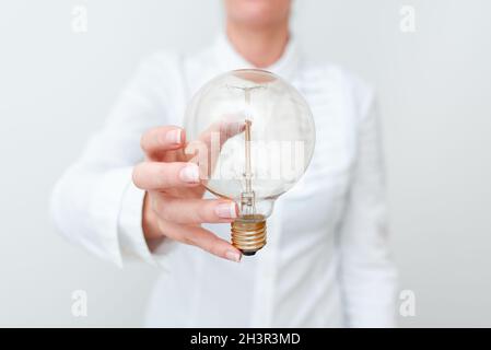 Lady Holding Lampe mit formellem Outfit präsentiert neue Ideen für Projekt, Business Frau zeigt Glühlampe W Stockfoto