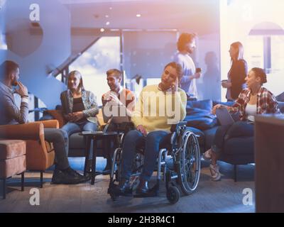 Porträt einer behinderten Geschäftsfrau im Rollstuhl vor Ihr vielseitiges Geschäftsteam im Büro Stockfoto