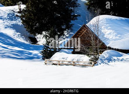 Romantische Holzhütte in tief verschneite Winterlandschaft in Tirol mit großem Schnee auf dem Dach der Hütte Stockfoto