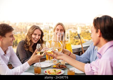 Fröhliche Freunde trinken während der Dachparty Weißwein Stockfoto