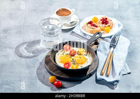 Spiegeleier in gusseisernen Spiegeleiern. Konzept für ein sonniges Frühstück am Morgen Stockfoto