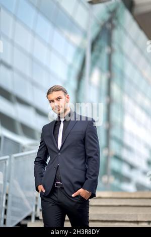 Hübscher, stilvoller junger Geschäftsmann, der im Freien ein Porträt posiert Stockfoto