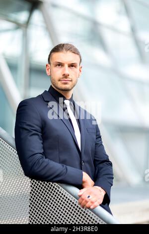 Hübscher, stilvoller junger Geschäftsmann, der im Freien ein Porträt posiert Stockfoto