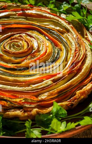 Gemüsekuchen mexikanische Sonne. Runde, offene Torte aus Zucchini, Auberginen und Karotten. Nahaufnahme von oben. Gesunde pflanzliche Lebensmittel. Vegetarismus. Spiralherb mit Auberginen. Stockfoto