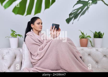Frau mittleren Alters, die sich im Winter im Herbst zu Hause ausruhen kann Stockfoto