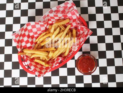 Pommes Frites im Retro Cafe mit kariertem Papier Stockfoto