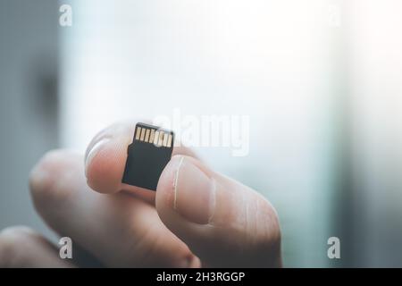 Der junge Mann hält eine kleine Speicherkarte in der Hand, Textraum Stockfoto