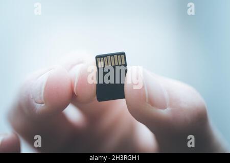 Der junge Mann hält eine kleine Speicherkarte in der Hand, Textraum Stockfoto