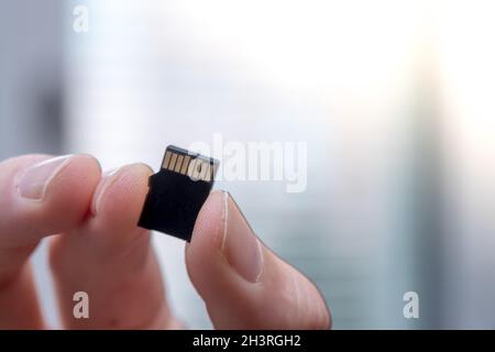 Der junge Mann hält eine kleine Speicherkarte in der Hand, Textraum Stockfoto