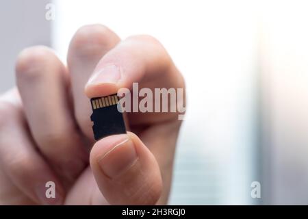 Der junge Mann hält eine kleine Speicherkarte in der Hand, Textraum Stockfoto