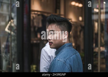 Nahaufnahme Porträt eines jungen, attraktiven asiatischen Mannes im Denim-Hemd. Chinesen, hübscher asiatischer Mann, echte Menschen auf den Straßen Stockfoto