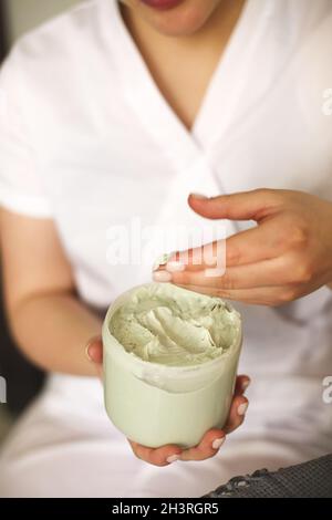 Crop Kosmetikerin mit Glas Creme im Salon Stockfoto