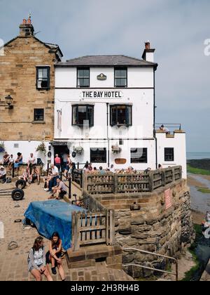 Das Bay Hotel und Besucher an einem geschäftigen Sommertag in Robin Hood's Bay im North York Moors National Park, Yorkshire England Stockfoto