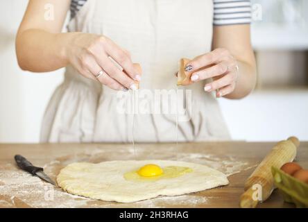 Crop Frau bereitet Teig am Tisch zu Hause Stockfoto