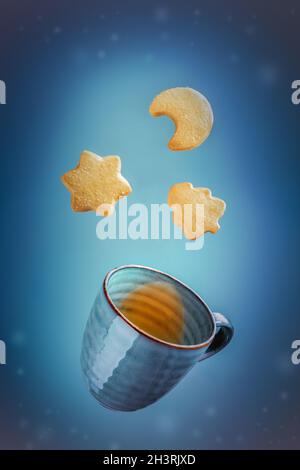 Weihnachtskarte mit herabfallenden Butterkeksen und einer Tasse Tee Stockfoto